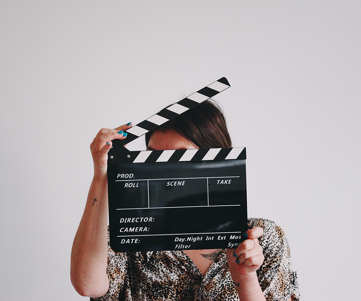 Frau mit Filmklappe als Symbol für Medienwissenschaft